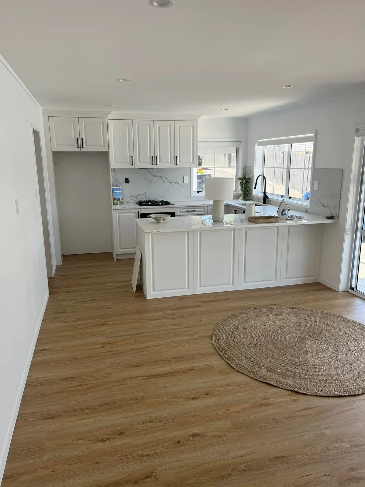 Renovated white kitchen with a stone waterfall island in Auckland